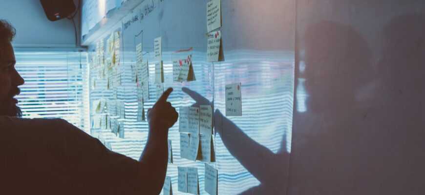 person pointing white paper on wall