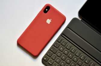 space gray iPhone with red case beside tablet keyboard